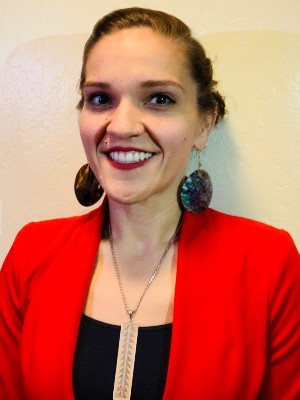 Melissa Eidman smiling wearing a red blazer and large abalone earrings